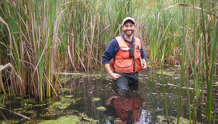 Andrew Rossi standing in deep water wearing waders and smiling at camera