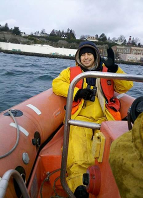 Erik Christensen on a rubber boat monitoring for murrelets and smiling at camera